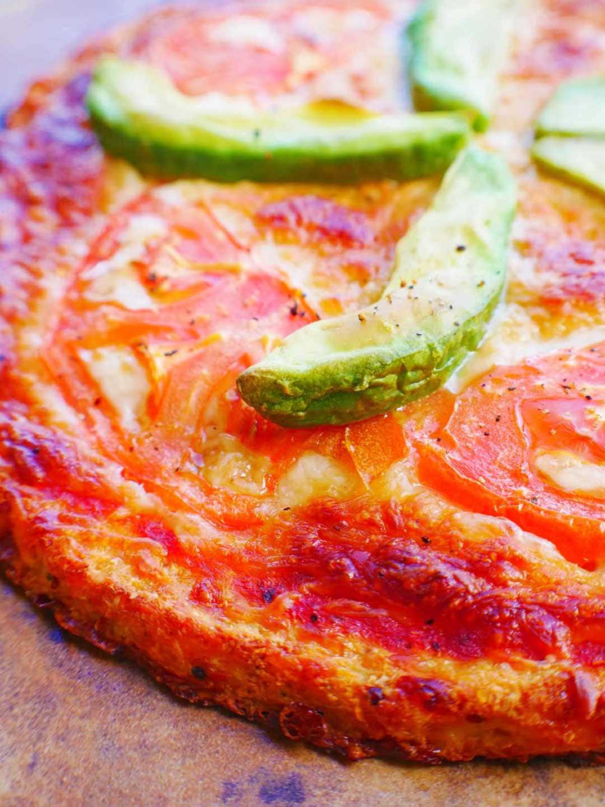 Cauliflower Pizza Crust baked with tomato sauce and avocados on top.