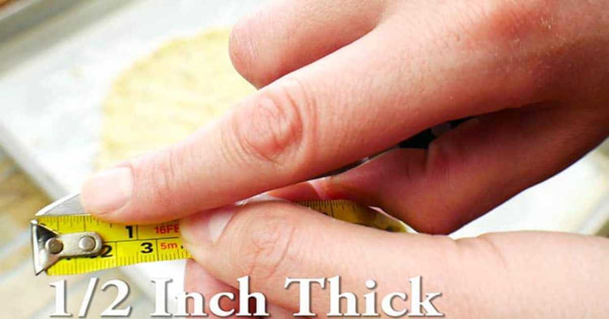 The pizza crust thickness being measured for accuracy to ensure crispy crust.