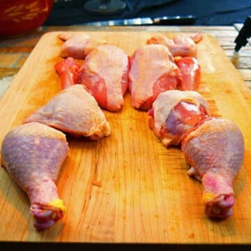 Whole chicken cut into 10 pieces on a wooden cutting board.