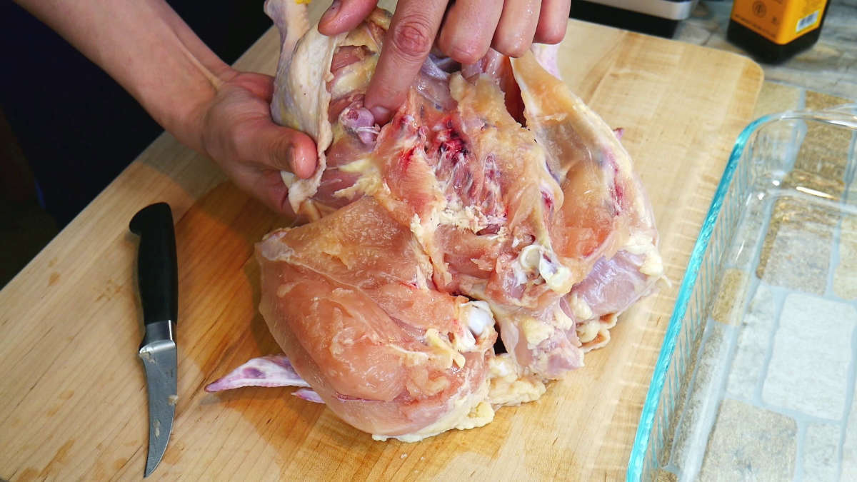 Finger poiniing at the location where to make the cut between the thigh and leg.