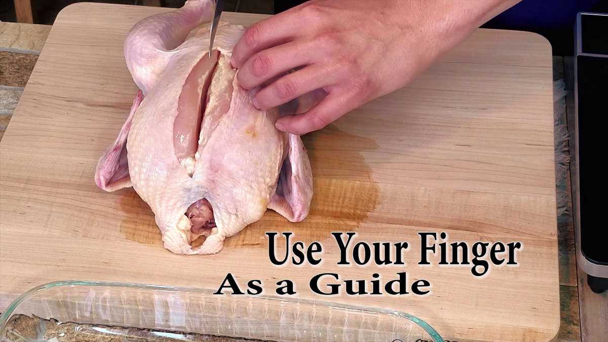 Using finger to find chicken backbone, using a knife to cut between the breast and bone.