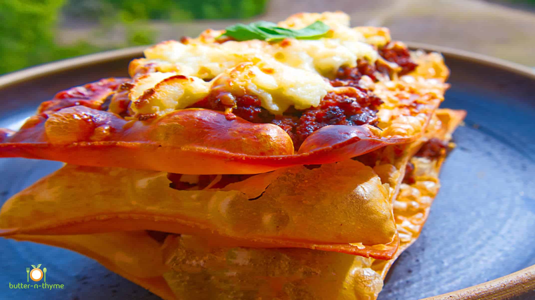 Crispy lasagna ready to serve on a black plate.
