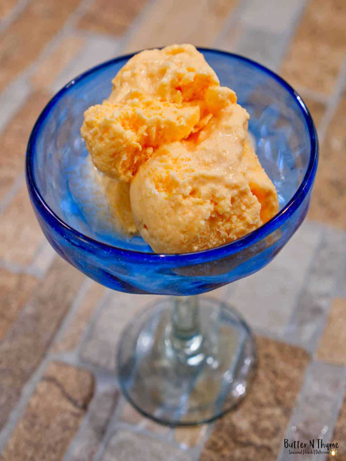 Cantaloupe ice cream in blue bowl on counter top.