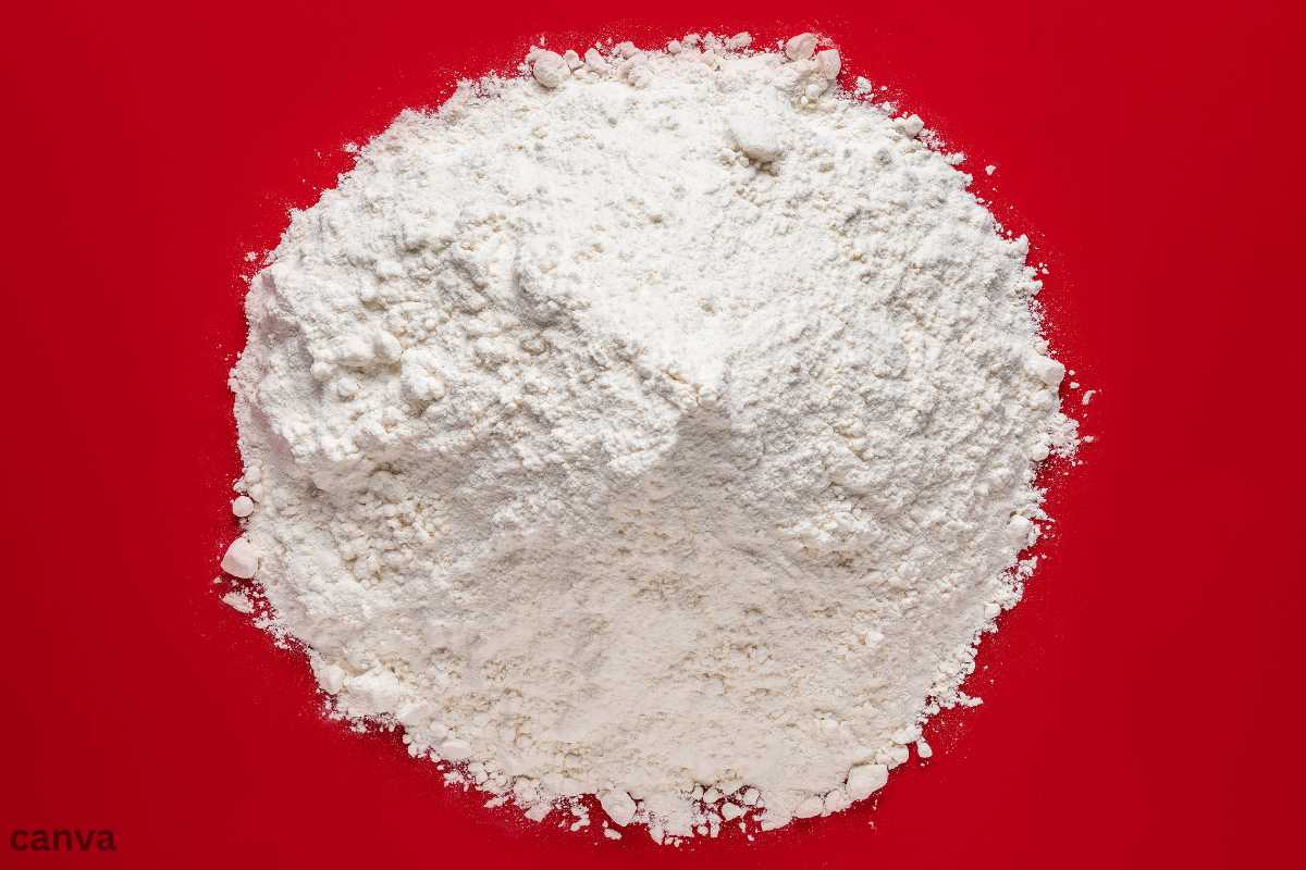 A pile of white bread flour on a bright red background, used for baking bread and pastries.