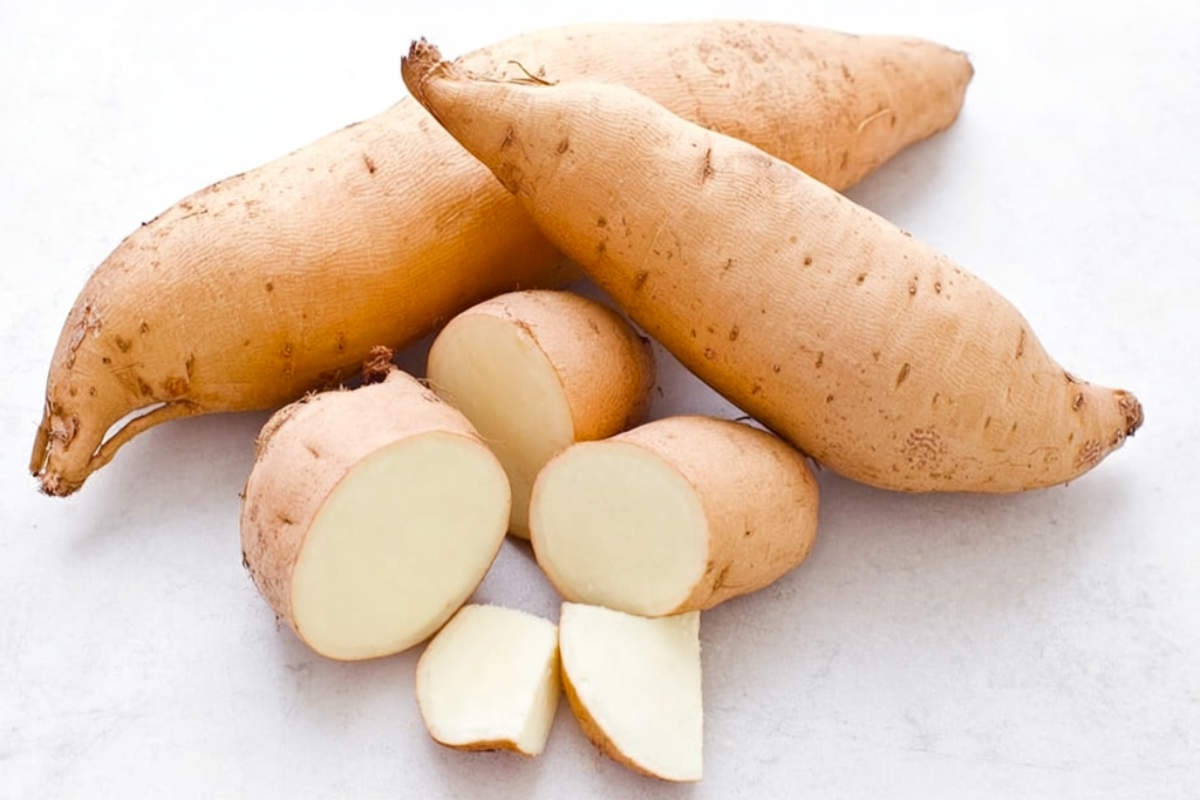 Hannah sweet potatoes with light tan skin and creamy white flesh, whole and sliced on a white background.
