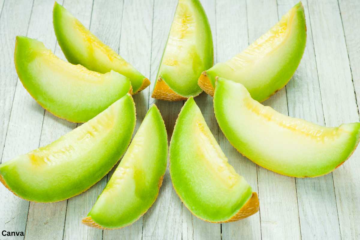 Freshly sliced honeydew melon wedges arranged on a light wooden surface.