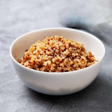 Fluffy cooked quinoa in a white bowl after cooking.