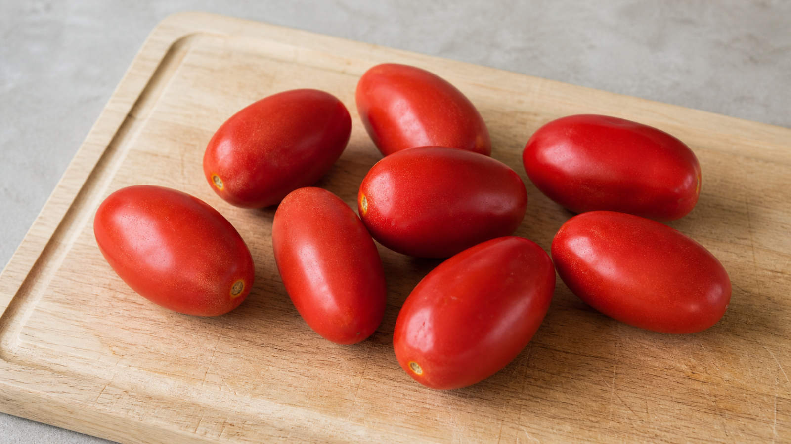 Whole red Roma tomatoes on a wooden surface