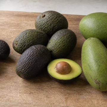 Small dark avocados, medium pebbly avocados, and larger green avocados arranged in three groups
