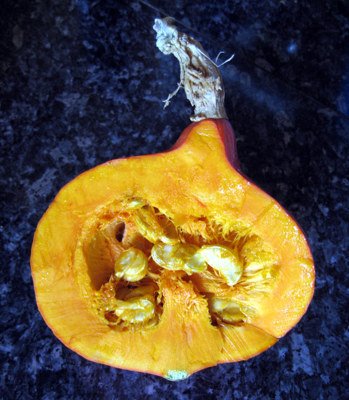 Ambercup squash cut in half showing orange flesh and seeds